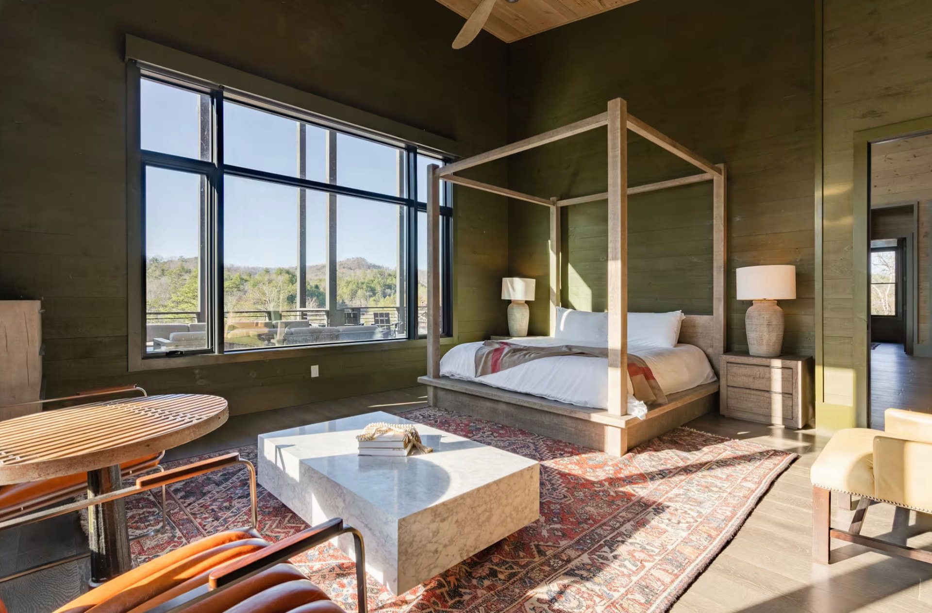 King bedroom with a light wood canopy bed, seating area, and wide mountain view