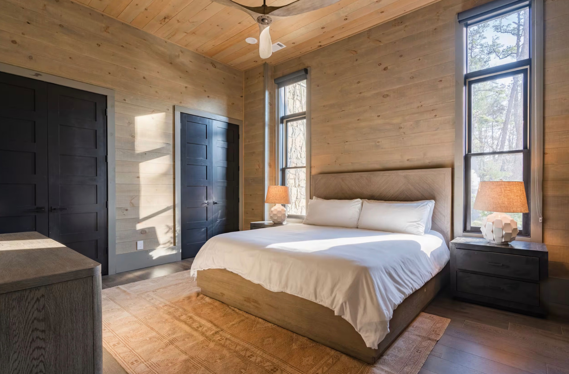 Bright king bedroom with cedar walls, crisp white linens, and tall windows