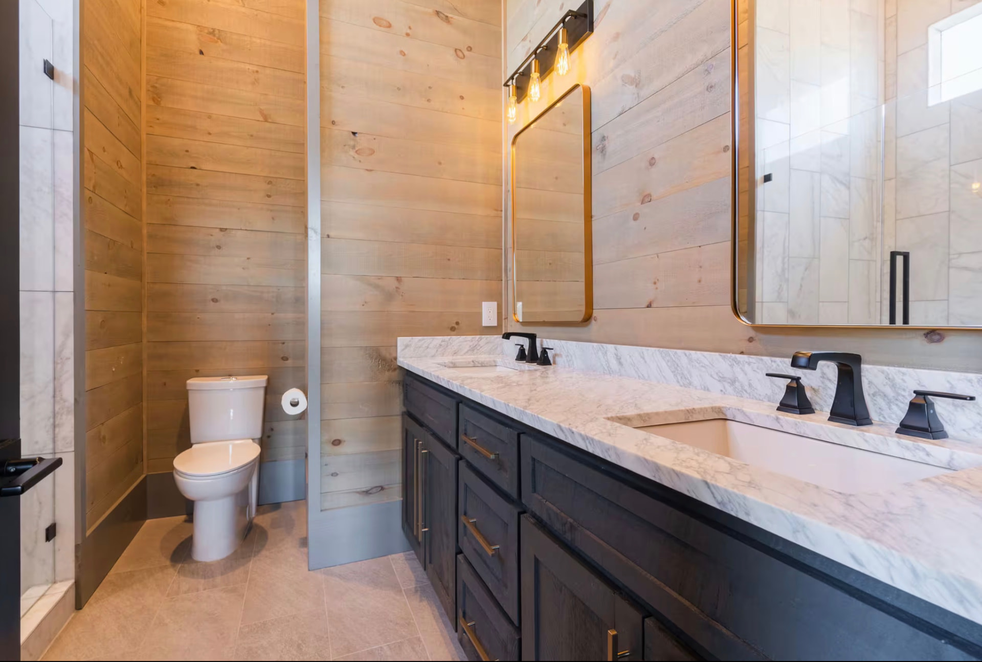 Bathroom with round mirror, marble countertop, and wood-paneled walls