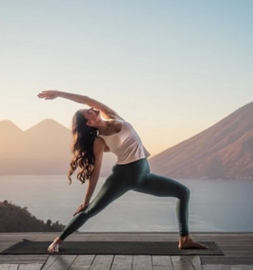 Kristen in an extended yoga pose overlooking the water
