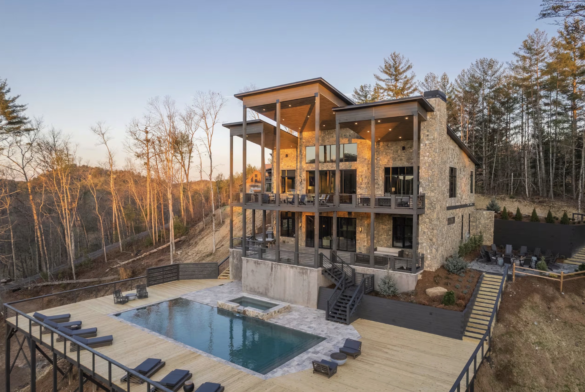 Modern stone retreat home with pool deck set into the Blue Ridge Mountains